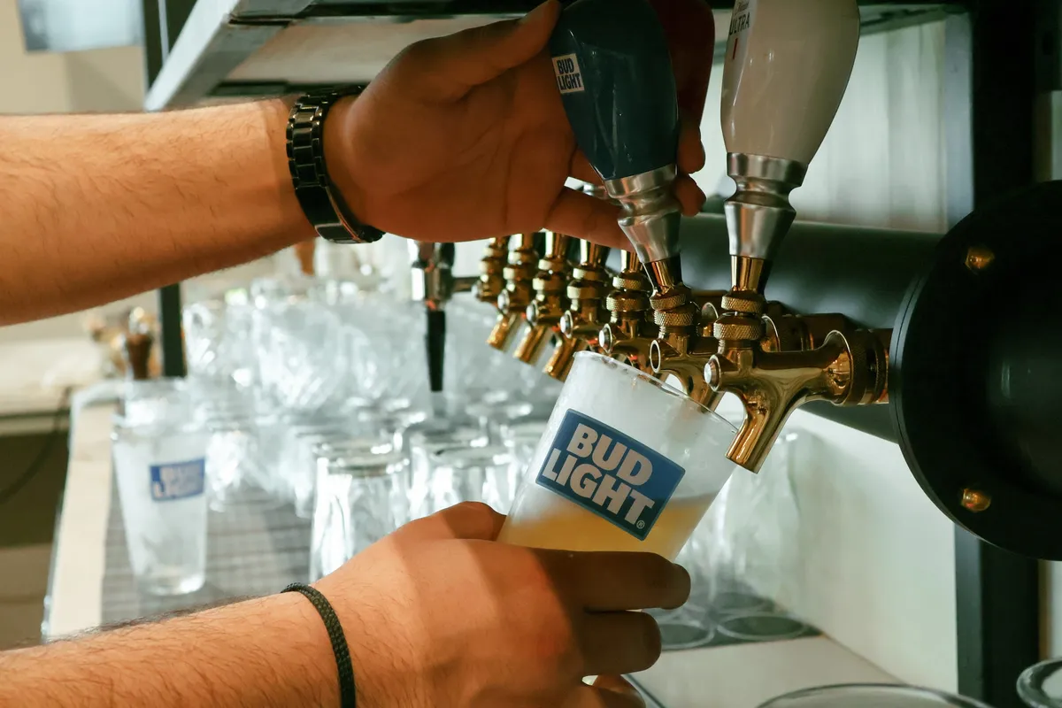 Hands pouring a draft beer from the taps into a glass.