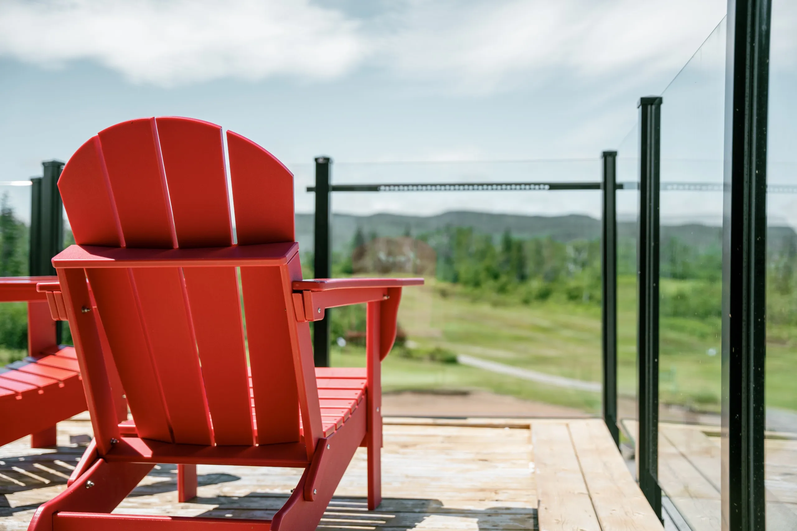 Red Adirondack chairs on a deck overlooking the fairways at Highlands Links.