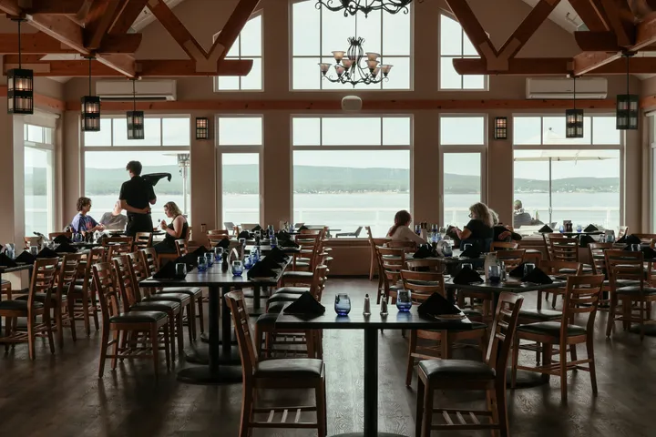Guests dining in the Arduaine restaurant under timber beams, with floor-to-ceiling windows looking out to the Atlantic.
