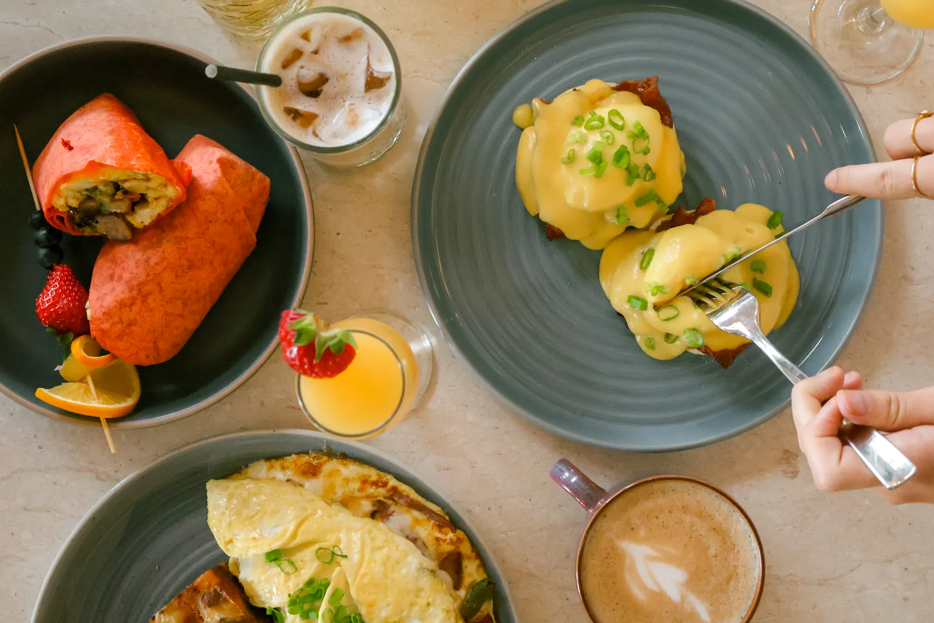 Breakfast plates with a wrap, eggs benedict, and an omelette.