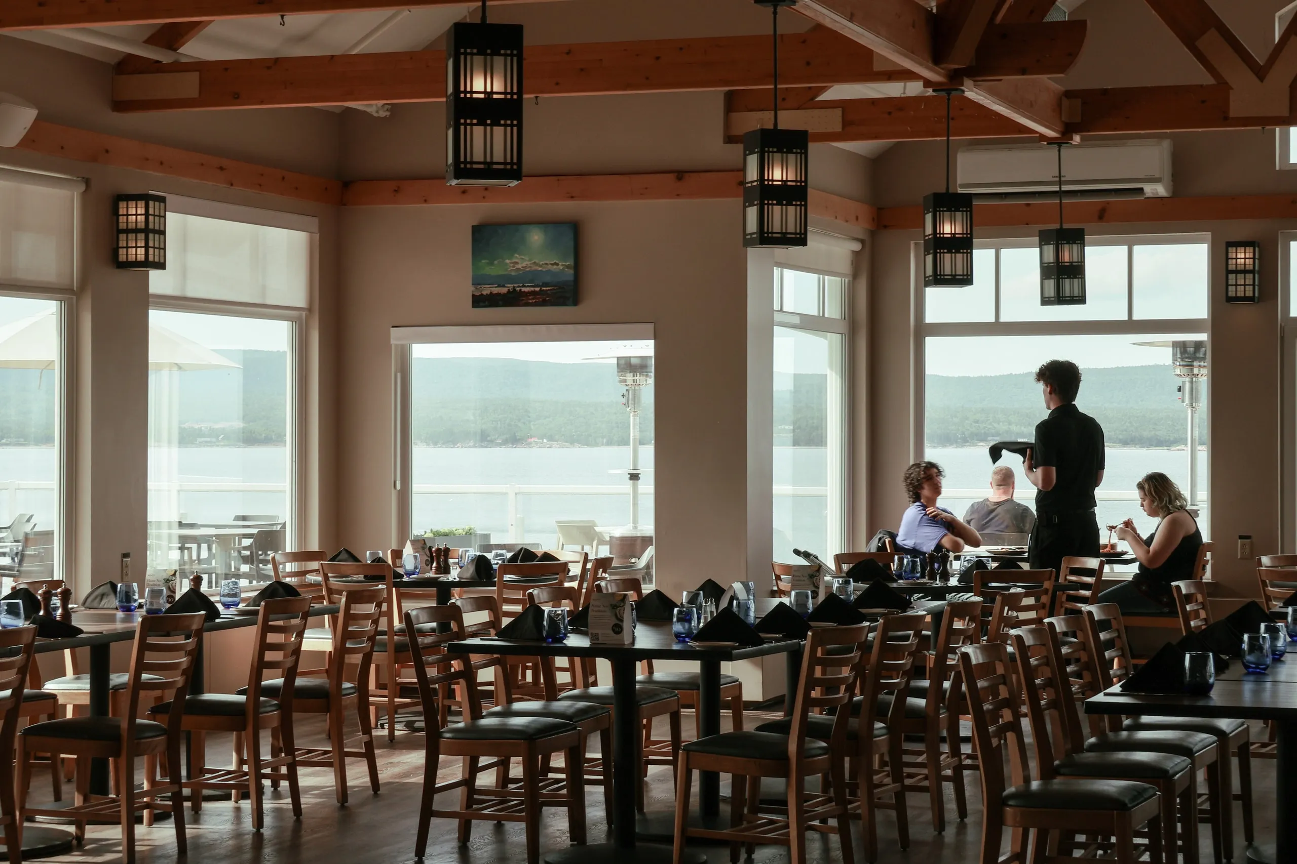 Guests seated in the dining room while a server stands by the window.
